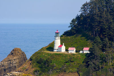 Lighthouse amidst sea and buildings against sky