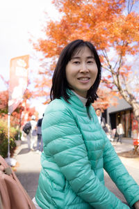 Portrait of smiling young woman standing during autumn