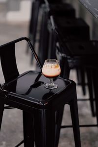 Close-up of frothy drink in wineglass on black bar stool