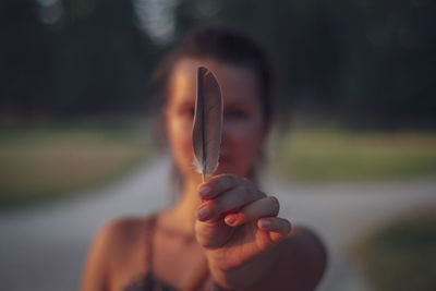 Close-up of woman hand holding feather during sunset