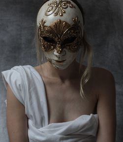 Portrait of woman wearing mask against wall