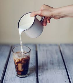 Close-up of hand pouring coffee in glass on table