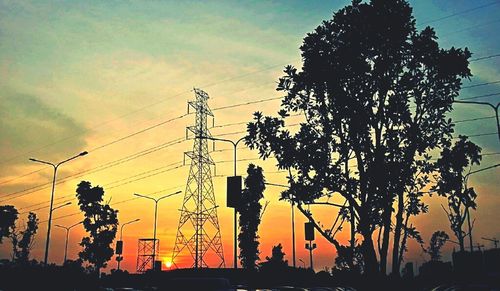 Low angle view of electricity pylon against cloudy sky