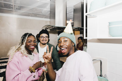 Portrait of cheerful multiracial male and female students in kitchen at college dorm