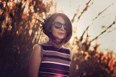 Portrait of smiling young woman standing against trees