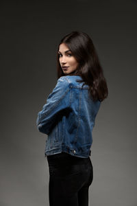 Portrait of woman standing against gray background