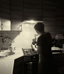 Rear view of man standing in kitchen at home