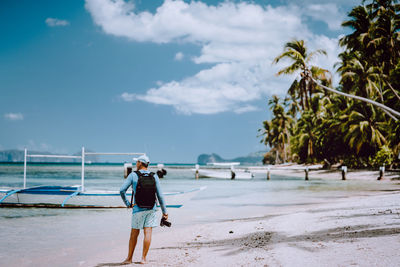 Rear view of man standing on beach against sky