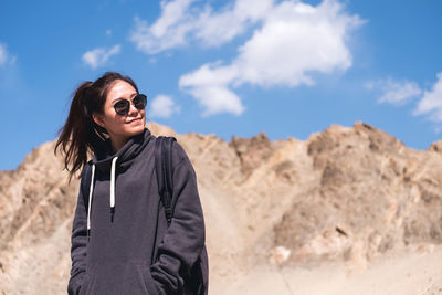 Woman in sunglasses standing against mountains