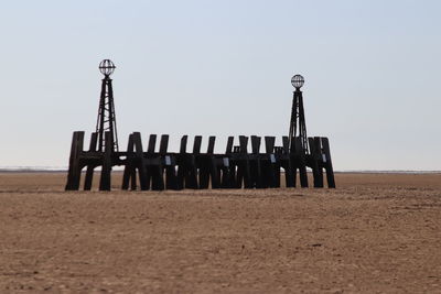 Wooden posts on beach against clear sky