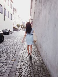 Full length rear view of woman walking on footpath