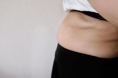 Midsection of woman standing against white background