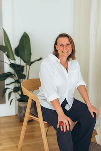 Portrait of young woman sitting on chair at home