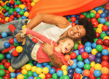 Happy father and daughter playing with multi colored balls in pool