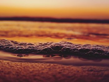 Surface level of beach against sky during sunset