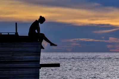 Silhouette man standing by sea against sky during sunset