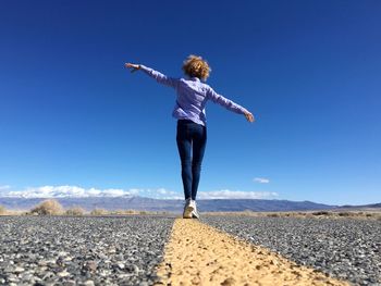 Rear view of woman on beach against clear blue sky