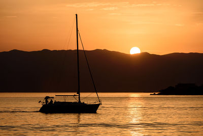 Silhouette sailboat sailing on sea against sky during sunset