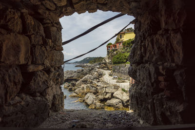 Rocks by sea against sky seen through arch window