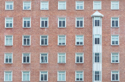 Orange brick wall vintage building. glass window of skyscraper apartment or hotel building in city.