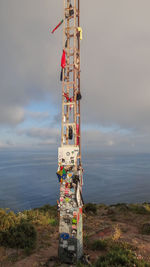 View of communications tower on sea shore against sky