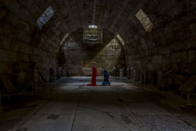 Side view of man kneeling by woman in abandoned building