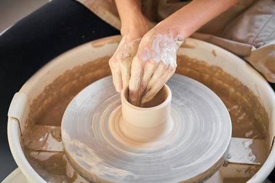 Cropped hands of potter making earthenware at pottery workshop