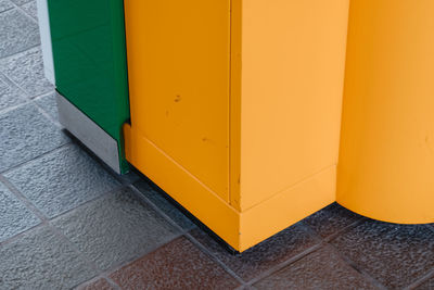 Close-up of yellow door on tiled floor against wall