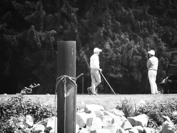 Rear view of men standing by plants in forest