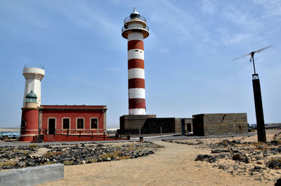 Low angle view of lighthouse by building against sky