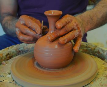 Midsection of man working in mud pottery
