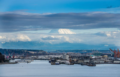 Clouds partially cover mount rainier which towers over the port of tacoma.