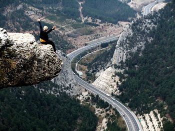 Rear view of man sitting on cliff