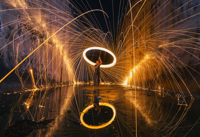 Man spinning wire wool while standing on street at night