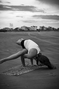 Full length of woman practicing handstand at beach