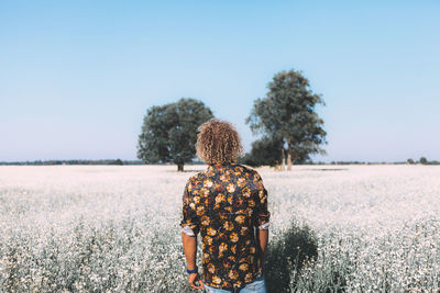 Rear view of man standing amidst flowering plants