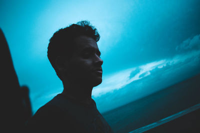 Side view of young man against sea and sky during dusk