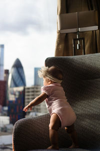 Rear view of baby girl standing on a chair