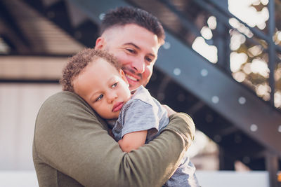 Boy leaning on dad's shoulder while dad smiles