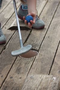 Low section of child playing golf on boardwalk