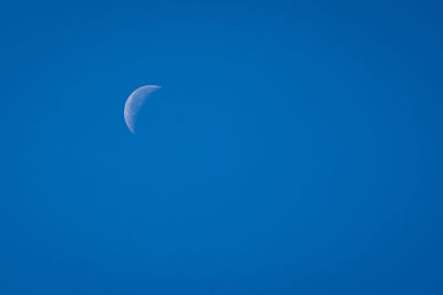 Low angle view of moon against blue sky