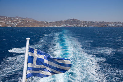 Greek flag against sea on sunny day