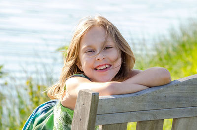 Smiling girl with wind blown hair posing as she sits on a bench