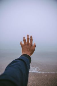 Cropped hand gesturing at beach