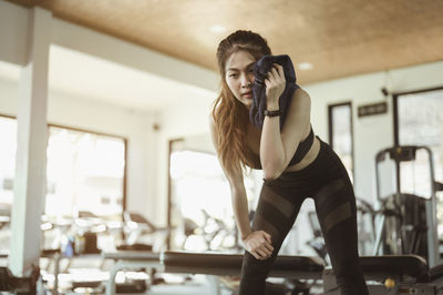 Young woman wiping face with towel in gym