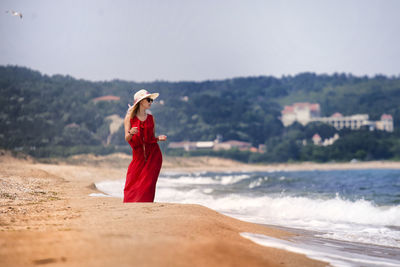 Woman standing at beach against sky