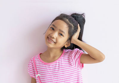 Portrait of smiling girl standing against white background