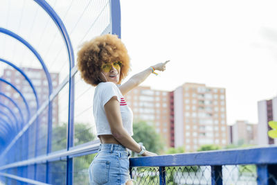 Woman with afro hair pointing on a bridge