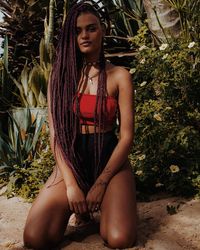 Portrait of young woman sitting against plants