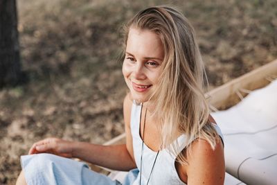 Smiling woman sitting on deck chair looking away